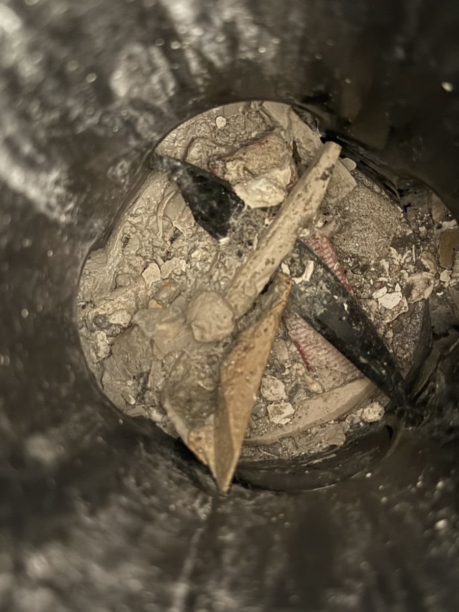 צילום פנימי של קו ניקוז ובו פסולת בנייה, שברי חומר ומסמרים